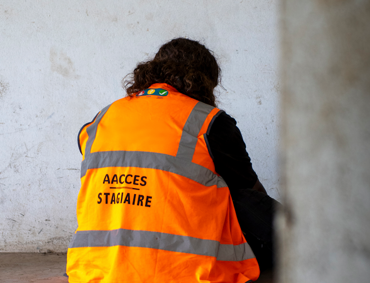 Stagiaire en gilet orange AACCES assis contre un mur, illustrant la formation à la résilience psychologique en contexte opérationnel